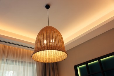 Stylish pendant lamp on ceiling indoors, low angle view