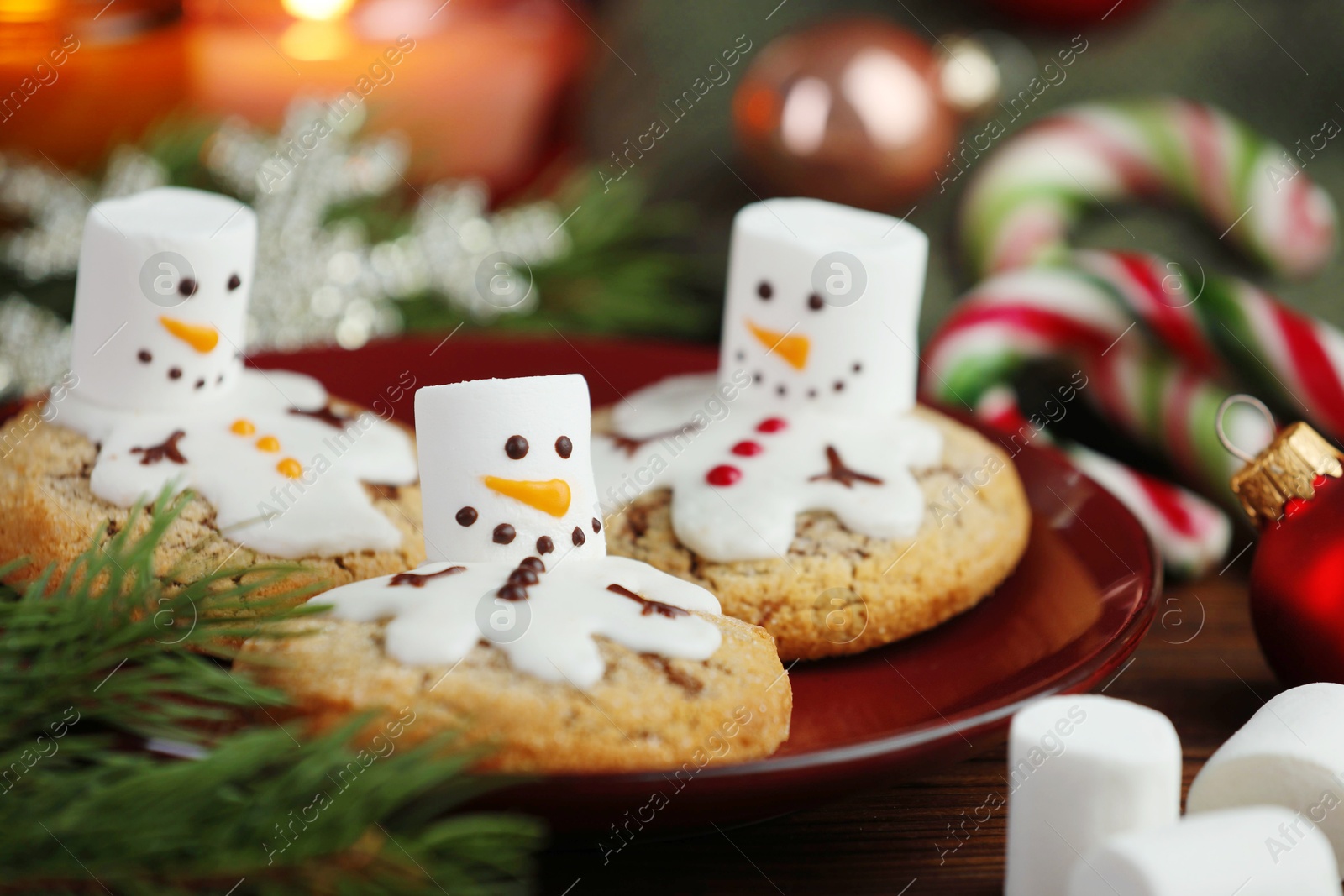 Photo of Funny marshmallow snowmen, cookies and festive decor on table, closeup