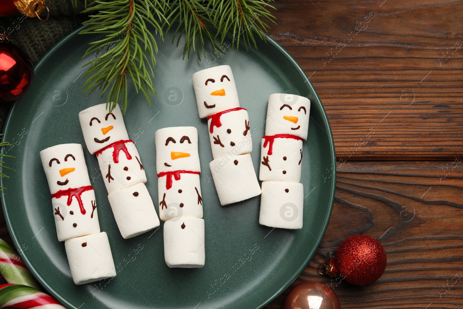 Photo of Funny marshmallow snowmen and festive decor on wooden table, flat lay