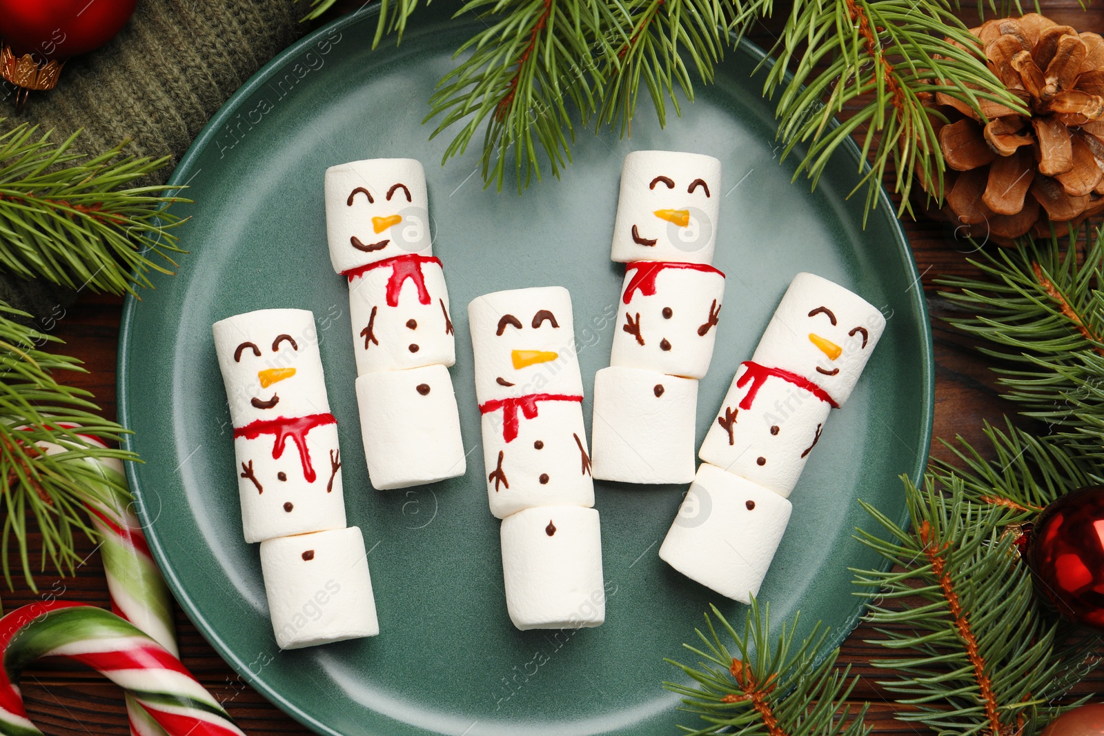 Photo of Funny marshmallow snowmen and festive decor on wooden table, flat lay