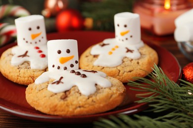 Photo of Funny marshmallow snowmen, cookies and festive decor on table, closeup