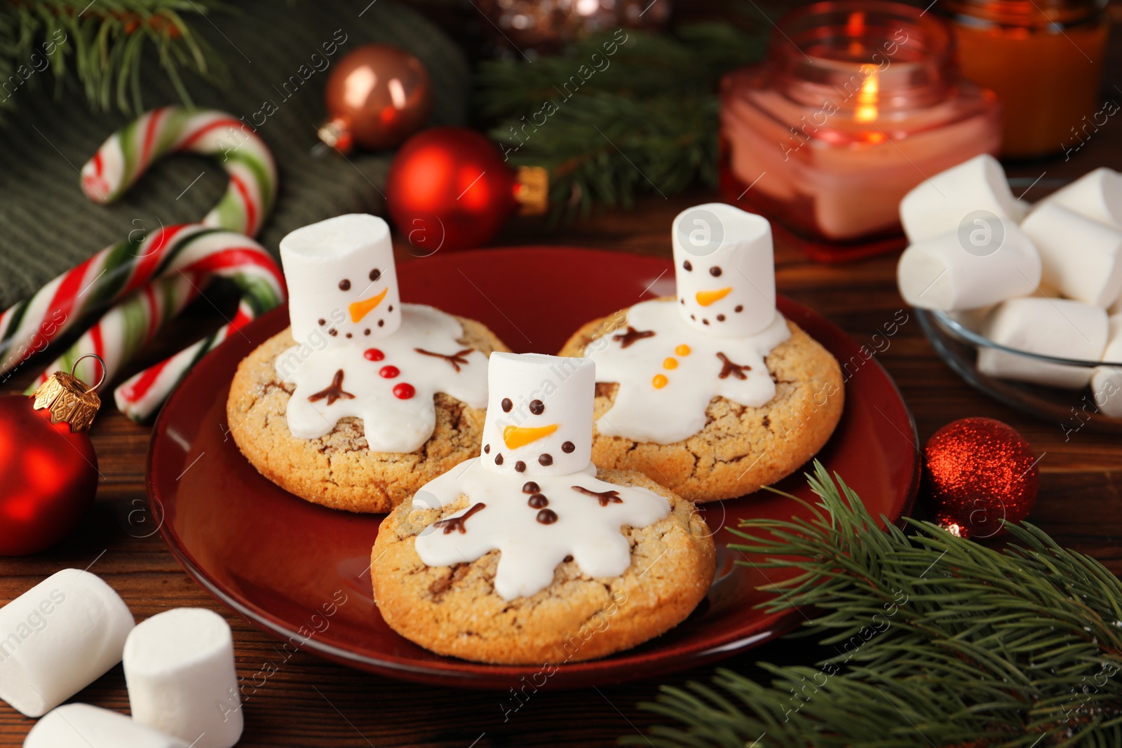 Photo of Funny marshmallow snowmen, cookies and festive decor on wooden table, closeup