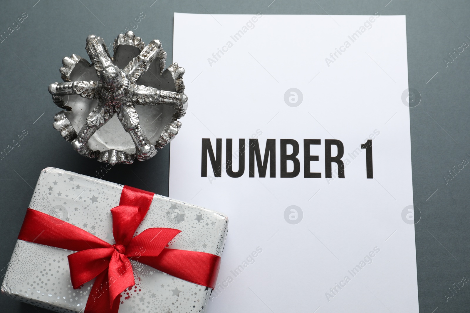 Photo of Sheet of paper with word Number 1, gift box and silver crown on grey table, flat lay