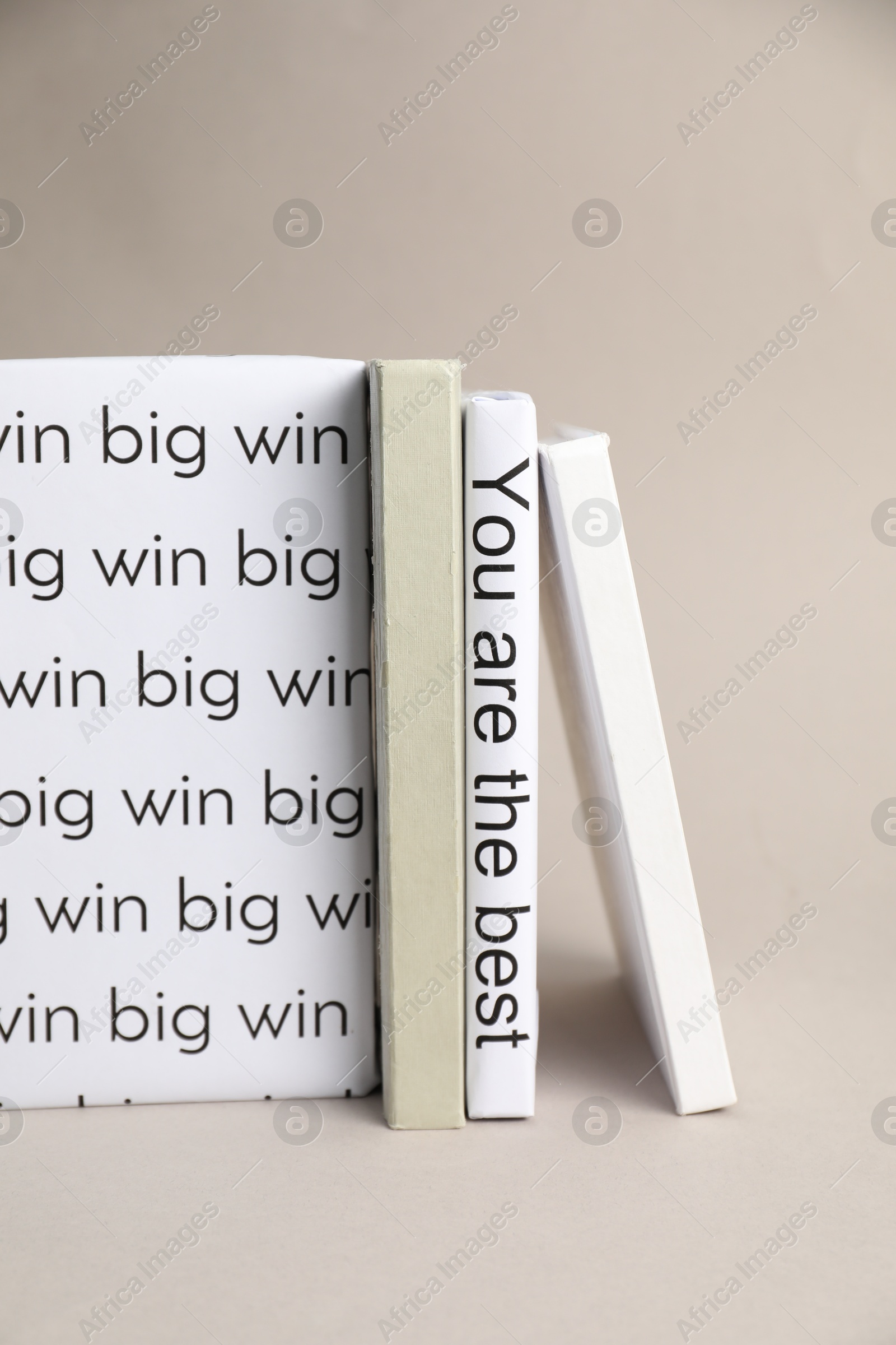 Photo of White books with phrases You are the best and Big win between ones on light grey background