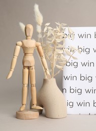 Photo of Wooden human figure, decorative plants and white book with words Big win on light grey background