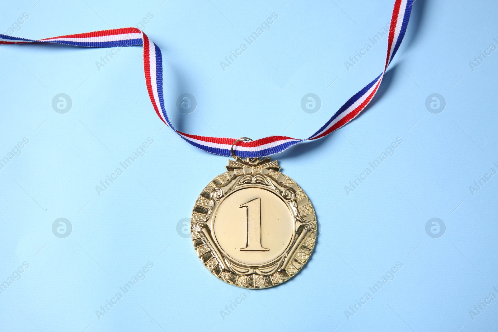 Photo of One golden medal on light blue background, top view