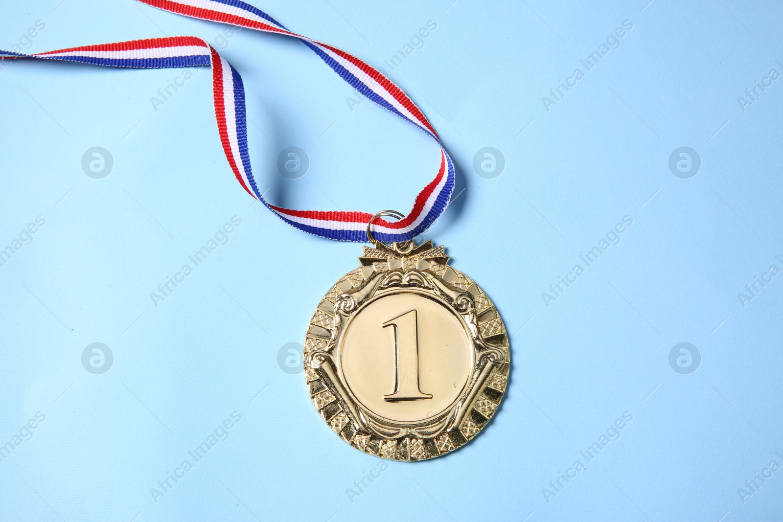 Photo of One golden medal on light blue background, top view