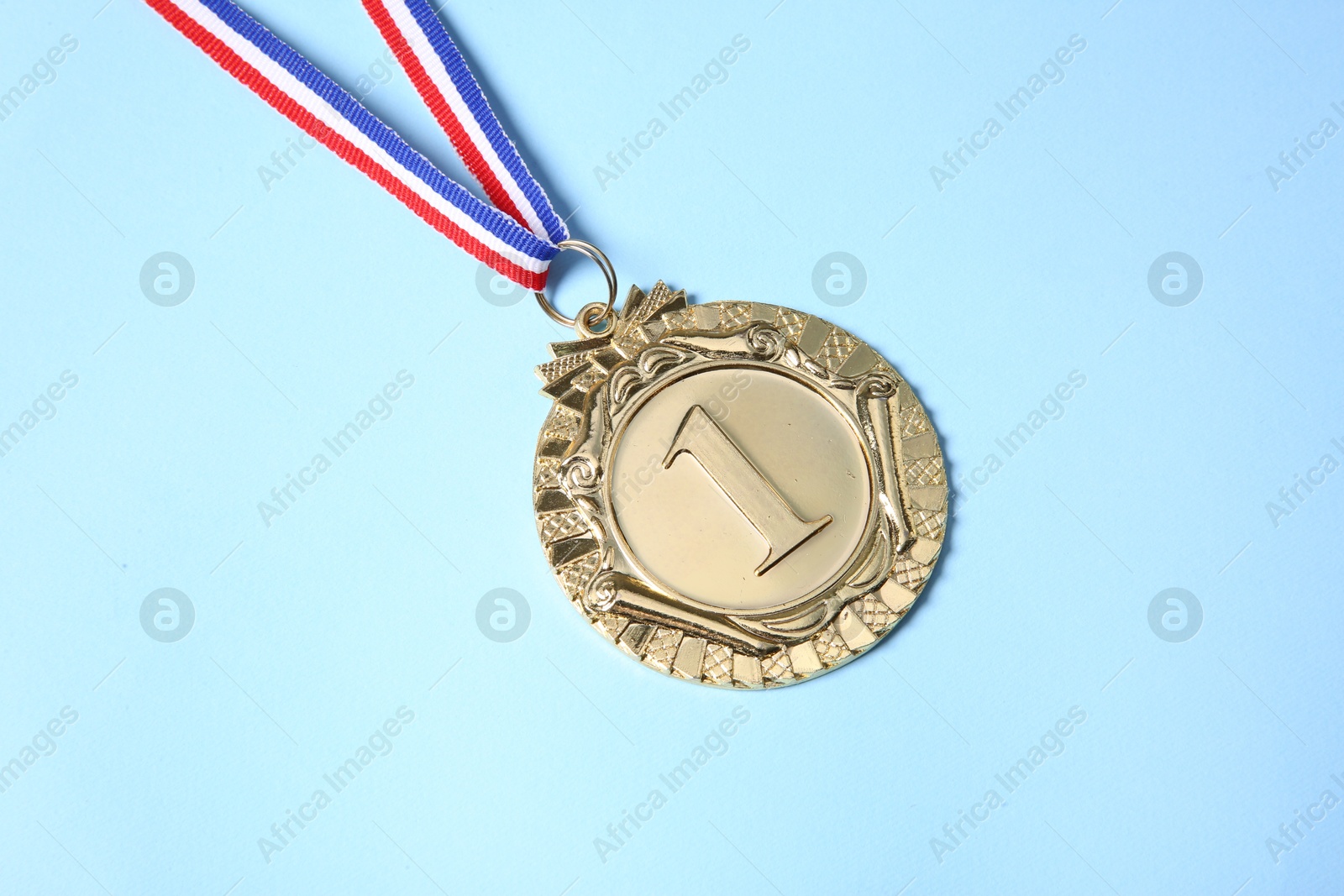 Photo of One golden medal on light blue background, above view