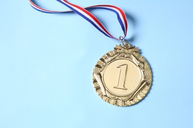 Photo of One golden medal on light blue background, top view