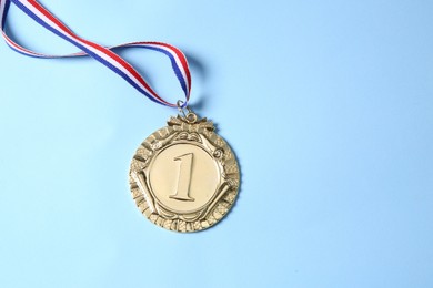 Photo of One golden medal on light blue background, top view. Space for text