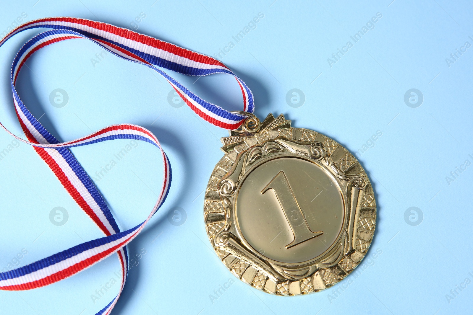 Photo of One golden medal on light blue background, top view