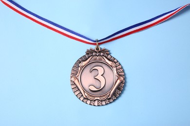 Photo of One bronze medal on light blue background, top view