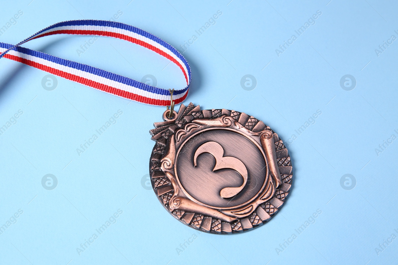 Photo of One bronze medal on light blue background, closeup