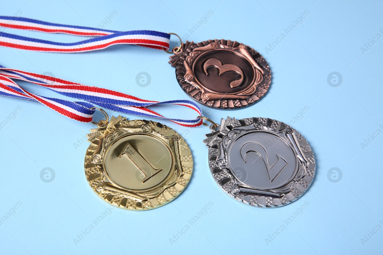 Photo of Different medals on light blue background, closeup