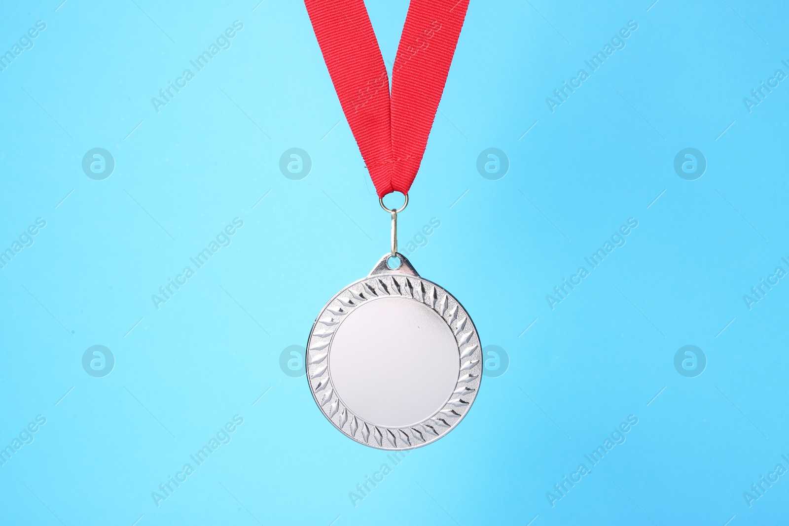 Photo of One silver medal with ribbon on light blue background