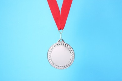 Photo of One silver medal with ribbon on light blue background