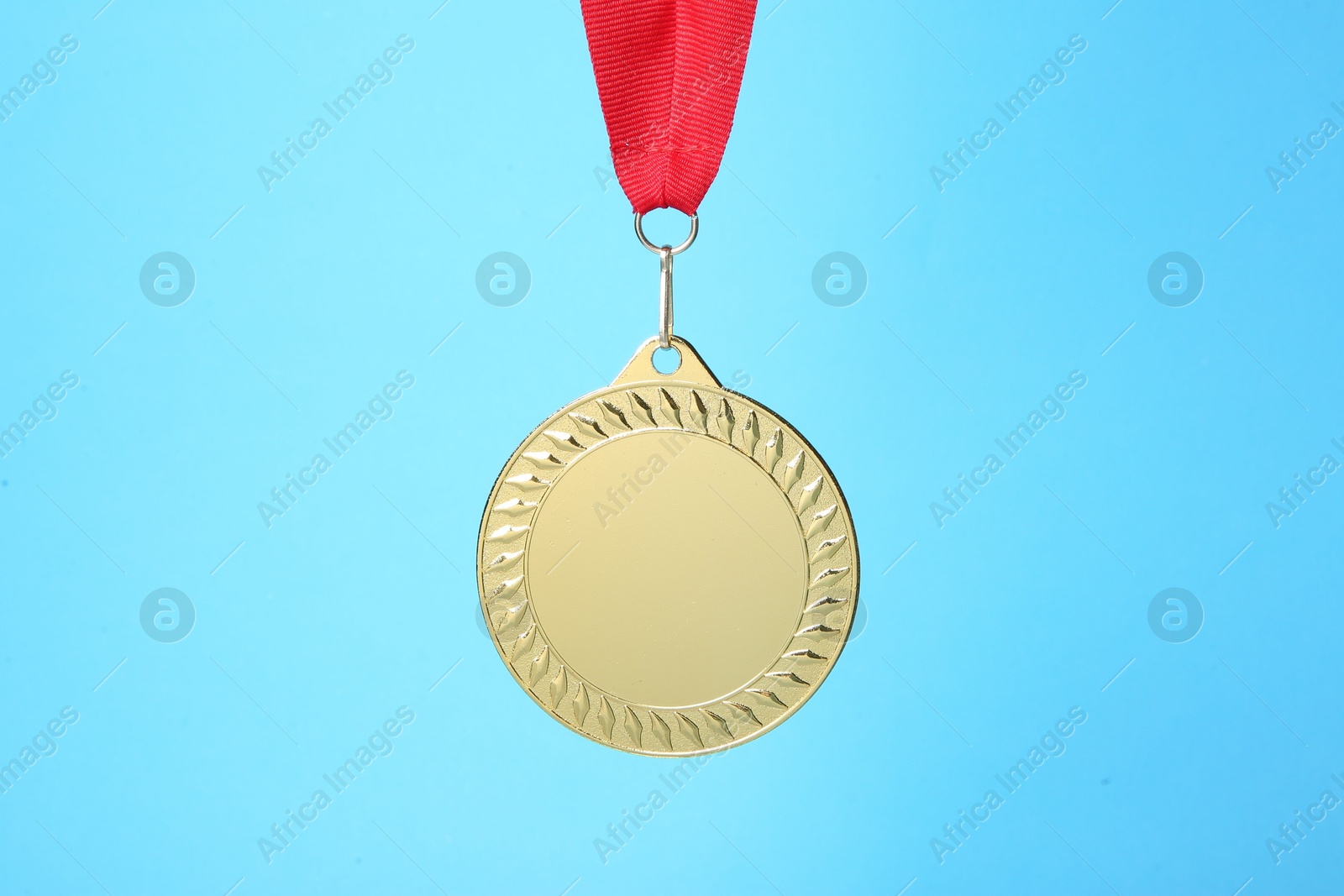 Photo of One golden medal with ribbon on light blue background