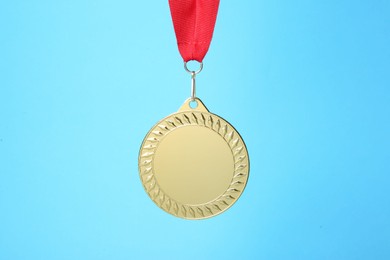 Photo of One golden medal with ribbon on light blue background