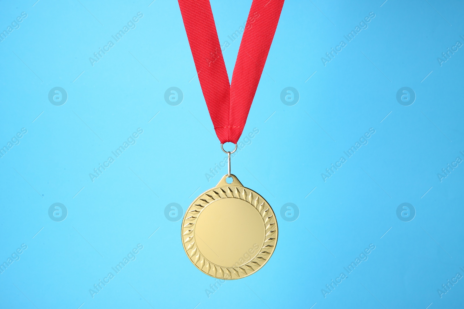 Photo of One golden medal with ribbon on light blue background