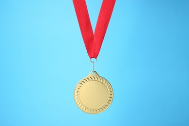 Photo of One golden medal with ribbon on light blue background