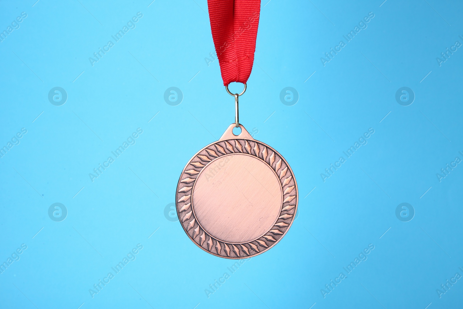 Photo of One bronze medal with ribbon on light blue background