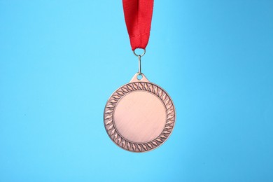 Photo of One bronze medal with ribbon on light blue background