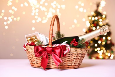 Wicker gift basket with sparkling wine and Christmas decor on white table