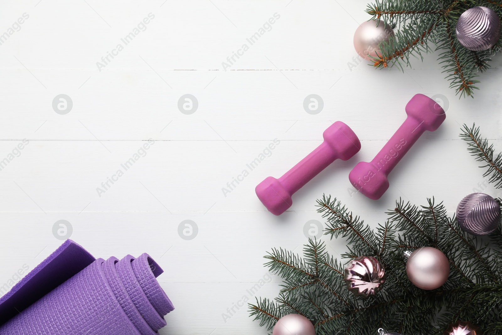 Photo of Dumbbells, mat, fir tree branches and Christmas baubles on white table, flat lay. Space for text