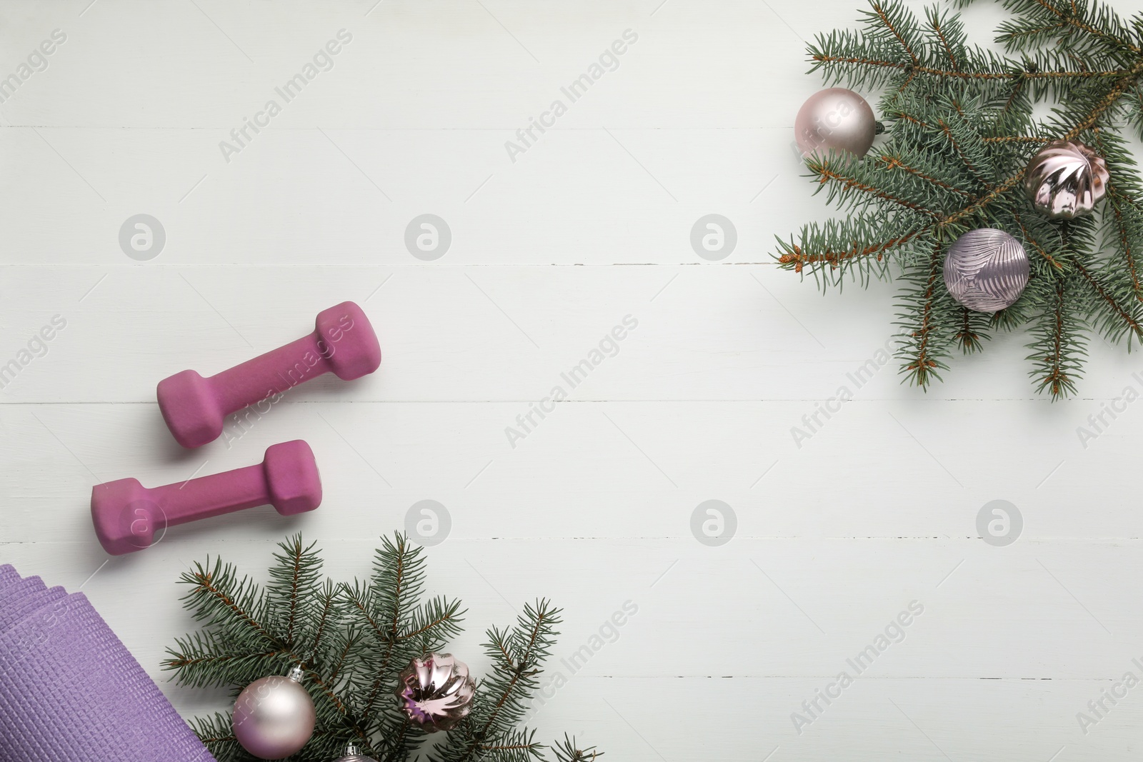 Photo of Dumbbells, mat, fir tree branches and Christmas baubles on white table, flat lay. Space for text