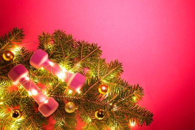 Photo of Dumbbells, fir tree branches and Christmas lights on bright pink background, top view. Space for text