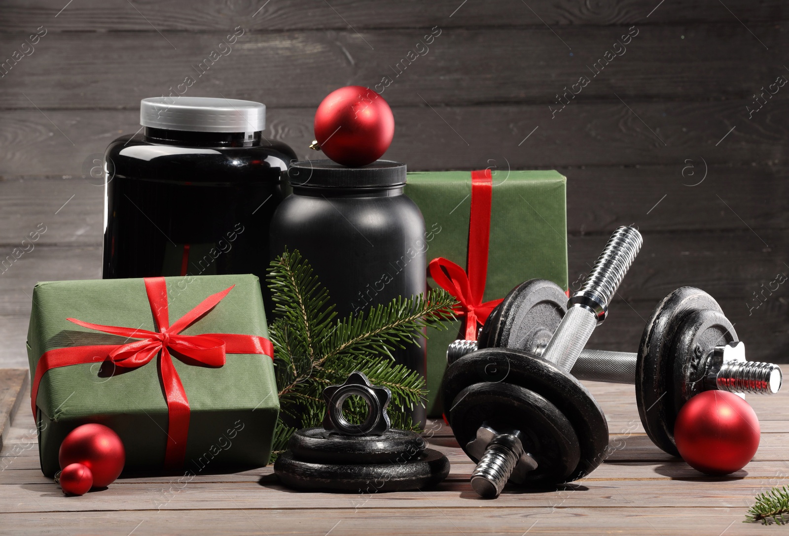 Photo of Dumbbells, containers with supplement and Christmas decor on wooden table