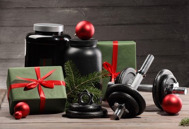 Photo of Dumbbells, containers with supplement and Christmas decor on wooden table