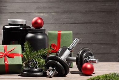 Photo of Dumbbells, containers with supplement and Christmas decor on wooden table