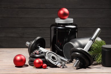 Photo of Dumbbells, containers with supplement and Christmas decor on wooden table