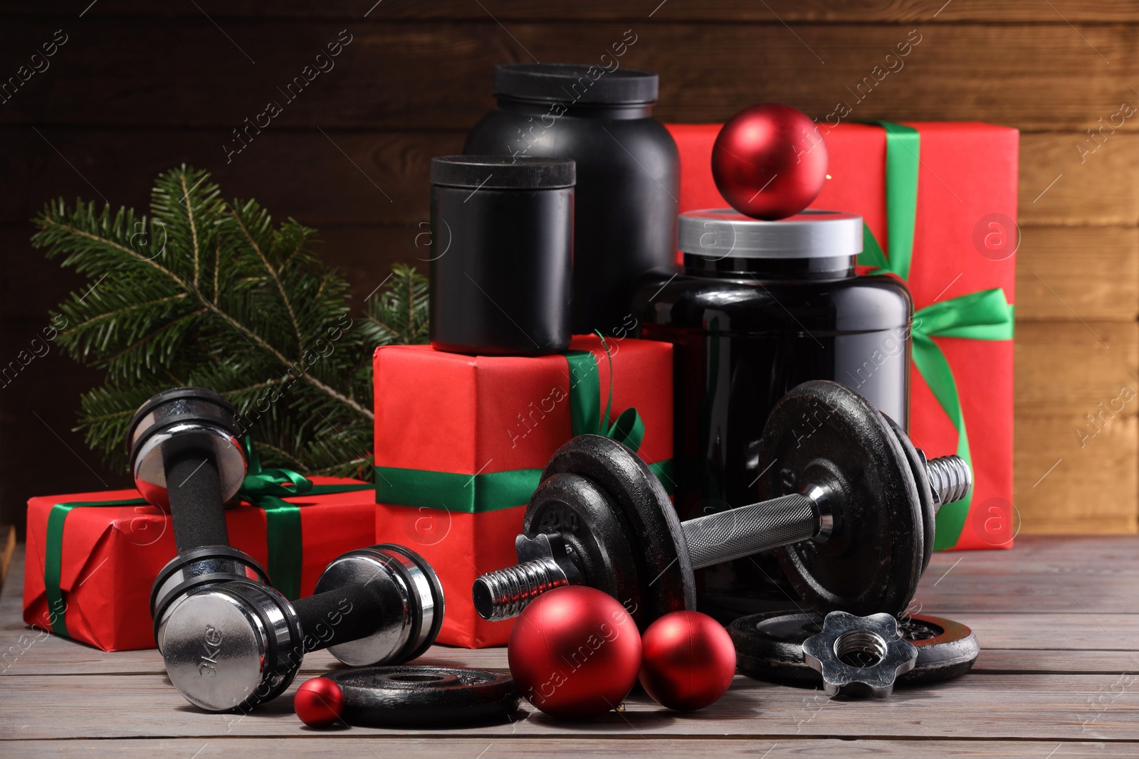 Photo of Dumbbells, containers with supplement and Christmas decor on wooden table