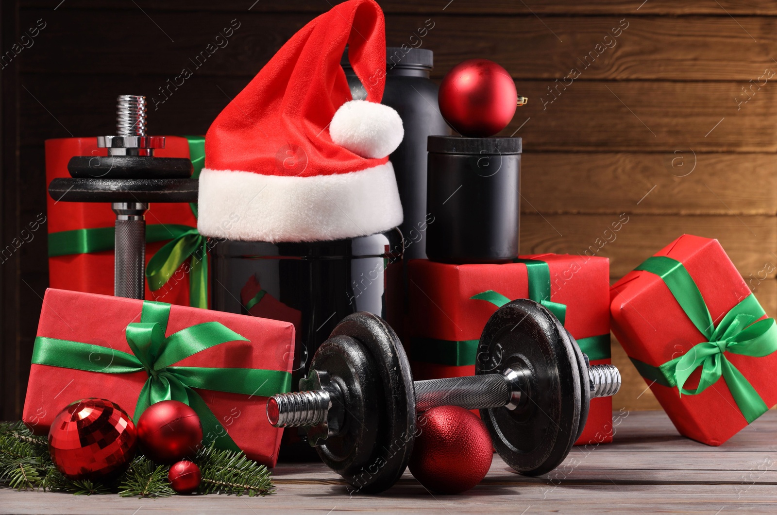 Photo of Dumbbells, containers with supplement and Christmas decor on wooden table