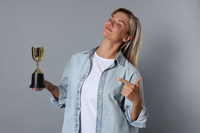 Photo of Happy winner with golden trophy cup on gray background