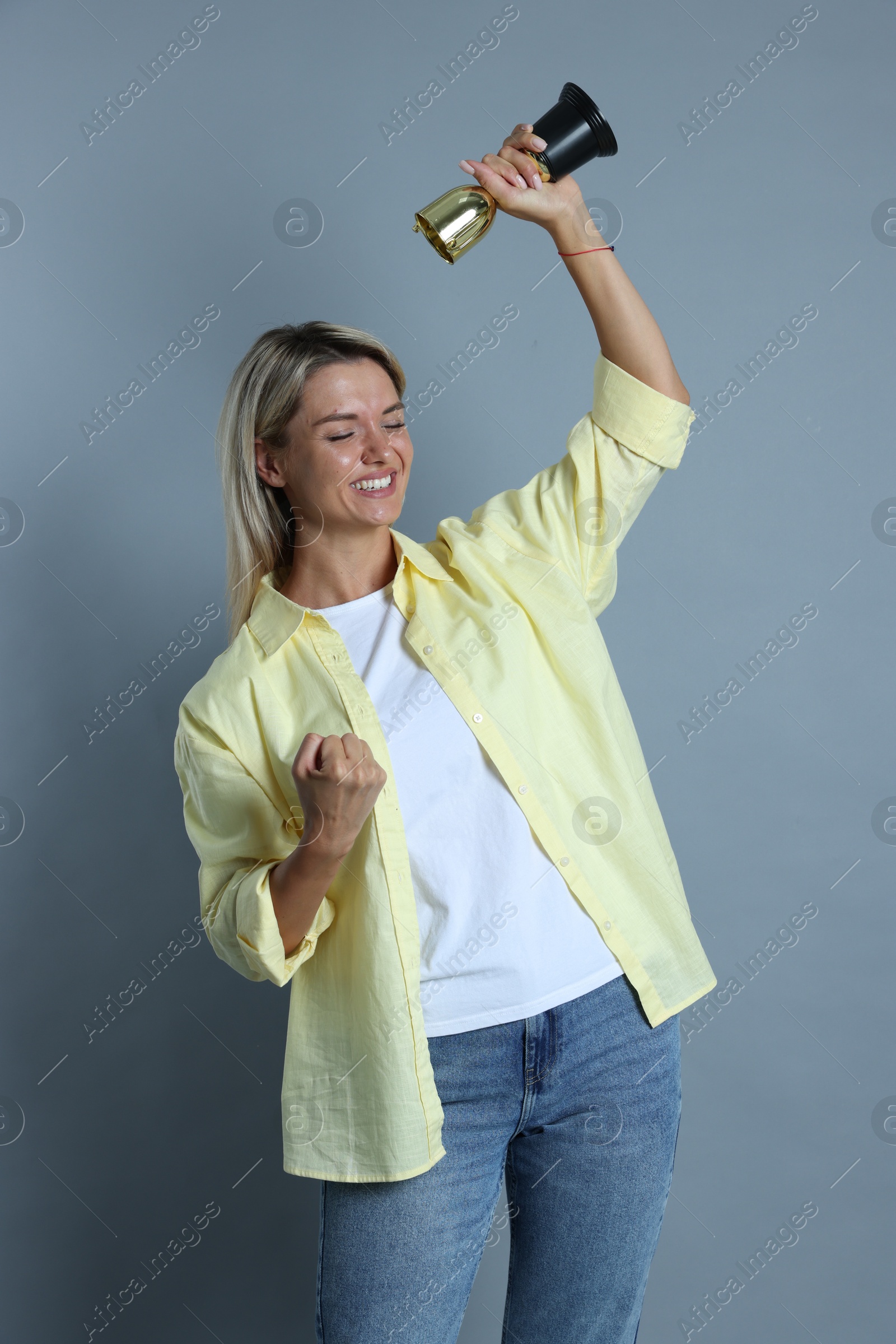 Photo of Happy winner with golden trophy cup on gray background,