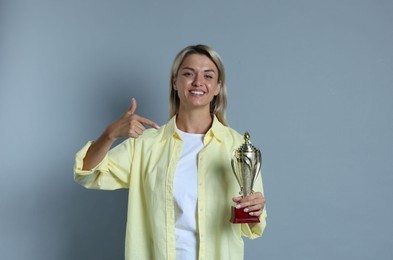 Photo of Happy winner with golden trophy cup on gray background,