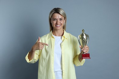 Photo of Happy winner with golden trophy cup on gray background,