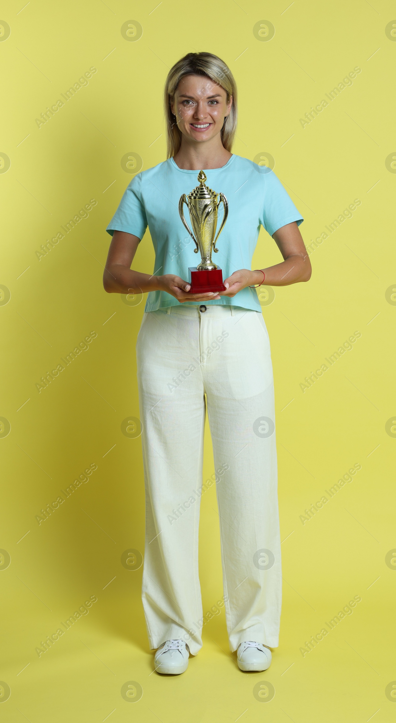 Photo of Happy winner with golden trophy cup on yellow background