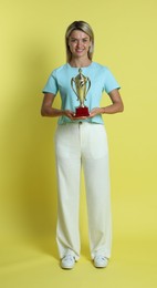 Photo of Happy winner with golden trophy cup on yellow background