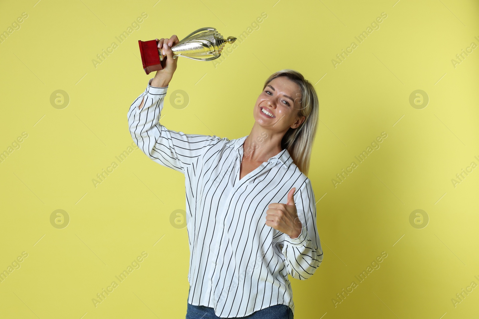 Photo of Happy winner with golden trophy cup on yellow background