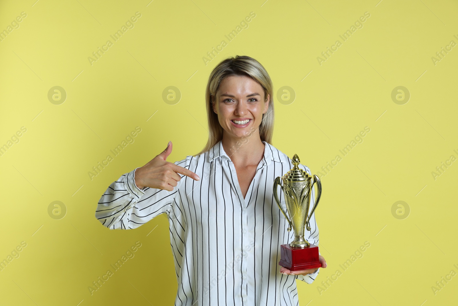 Photo of Happy winner with golden trophy cup on yellow background