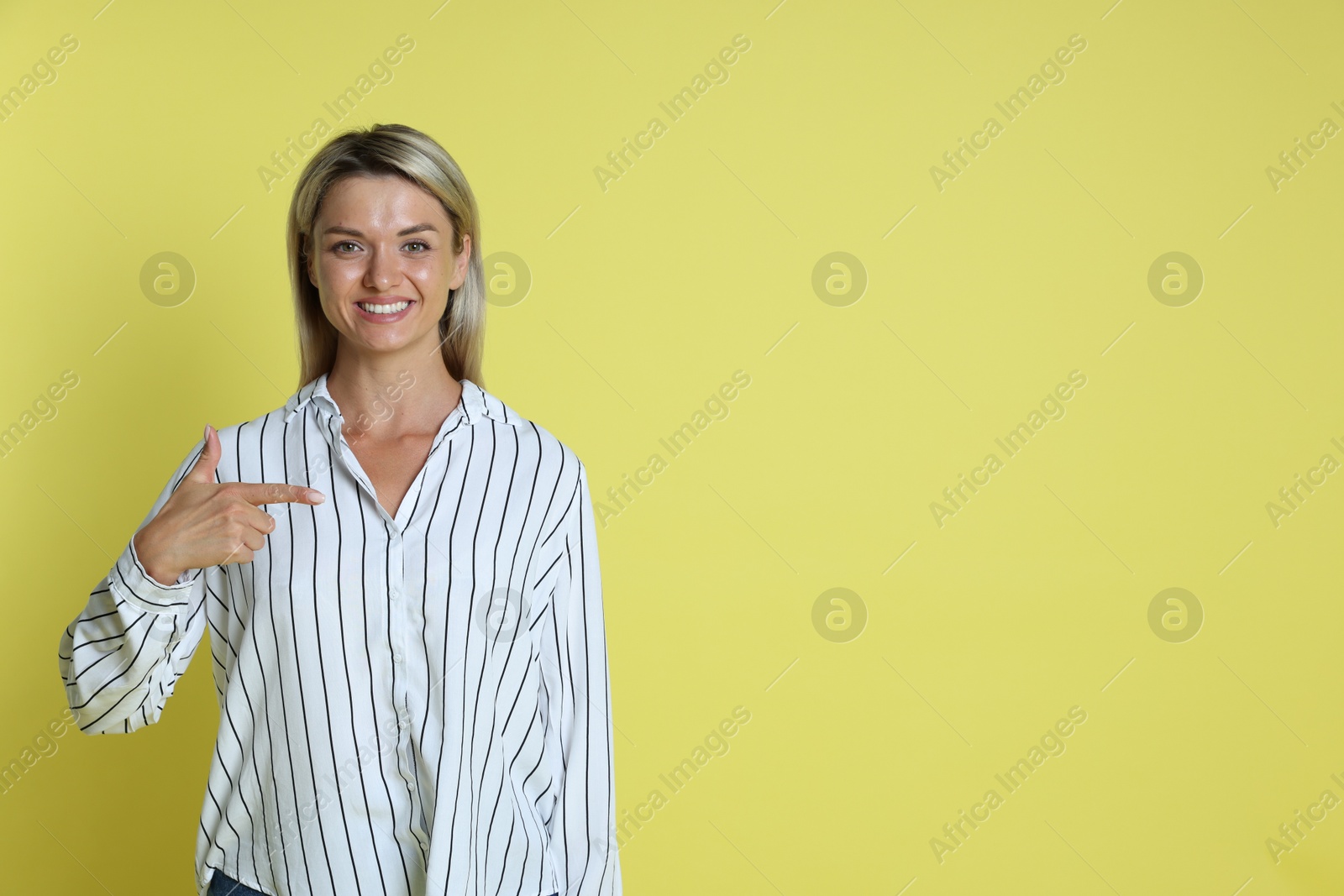 Photo of Happy winner pointing at something on yellow background, space for text