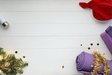 Photo of Flat lay composition with yoga mat and Christmas decor on white wooden background, space for text