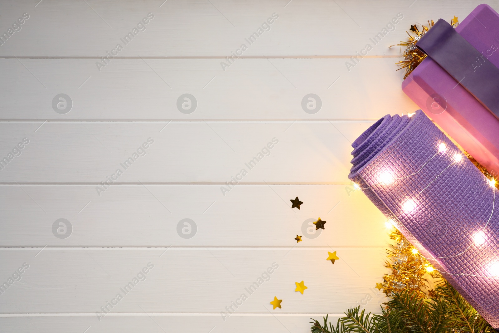 Photo of Flat lay composition with yoga mat and Christmas decor on white wooden background, space for text