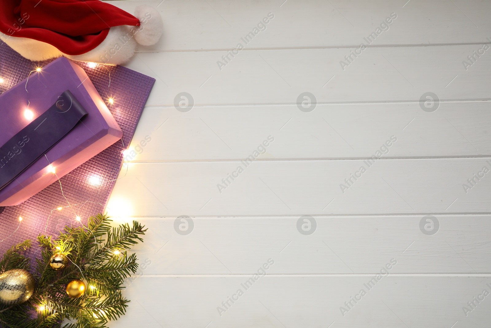 Photo of Flat lay composition with yoga mat and Christmas decor on white wooden background, space for text