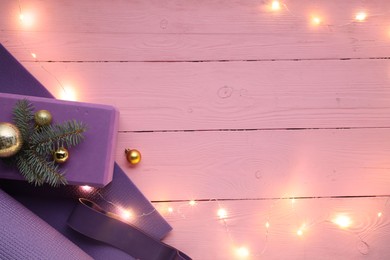 Photo of Flat lay composition with yoga mat and Christmas decor on pink wooden background, space for text