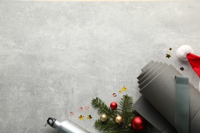 Photo of Flat lay composition with yoga mat and Christmas decor on gray textured background, space for text